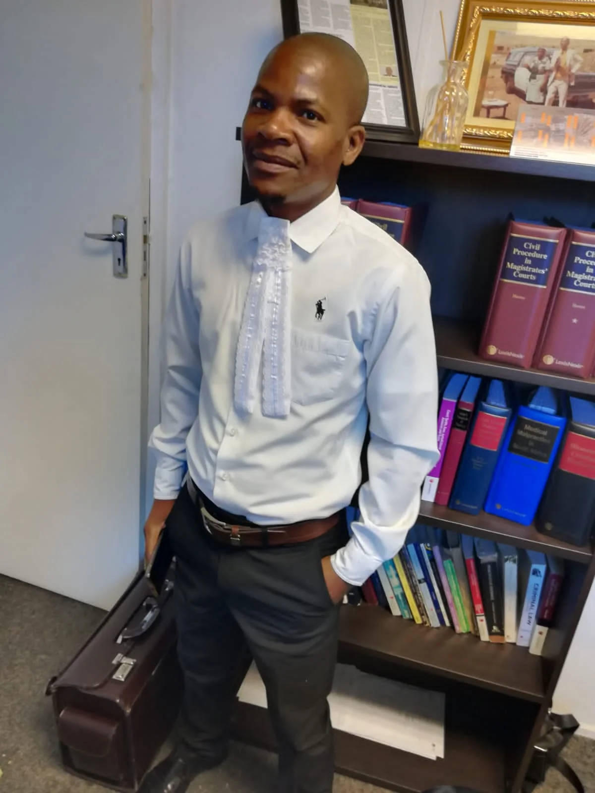 Mr. Osborn Ngobeni beside a library of South African legal texts
